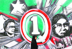 A Muslim woman walks past a painted wall of Maldives presidential candidates, Gasim Ibrahim (R) and Hassan Saeed, in Male on Friday. 