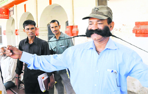 Railway loco pilot Chand Kumar shows his one and a half feet long moustache at the railway station in Bathinda on Sunday.