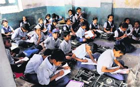 Students attend a class while sitting on the floor at a government school in Mani Majra