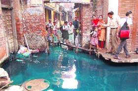 Schoolchildren cross a street with the help of benches in Hansliwali Gali in Katra Mit Singh area in Amritsar on Monday