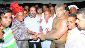 Winner Sonu receives the cash prize at the wrestling meet at Banipur in Rewari.