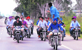  Youths, defying traffic norms, do triple-riding near Jalandhar on Monday. One of them is seen using his mobile to click photographs.