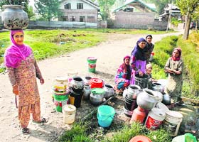 Daily grind: Women collect drinking water in metal pitchers from a channel west of Srinagar