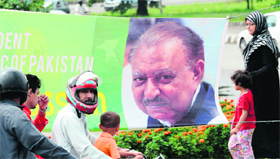 Commuters and pedestrians near a roadside banner welcoming incoming Pakistani President Mamnoon Hussain in Islamabad on Monday.