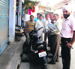 A Municipal Corporation team seals a shop as its owner fails to pay the house tax dues at Dam Ganj in Amritsar on Wednesday. 