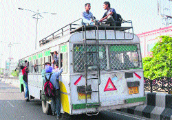 People hang on the doors and sit on the roof of a bus risking their lives in Bathinda. Tribune photo