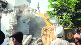 A JCB machine demolishes an illegal structure near the Tinkoni in Bathinda on Thursday.
