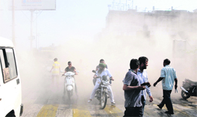 Commuters pass through a dust-filled road while the demolition drive by the MCB is under way nearby, at Tinkoni in Bathinda on Thursday.
