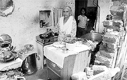 Sudarshan Puri cooks food in her kitchen, the wall of which has been pulled down by the Estate Office in Sector 16, Chandigarh