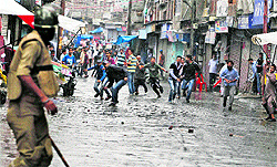 Supporters of the Jammu Kashmir Liberation Front throw stones at a CRPF jawan during a protest in Srinagar on Friday