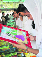 A student admires paintings at an exhibition at Government Women College in Jammu on Friday. Tribune photo: Inderjeet Singh