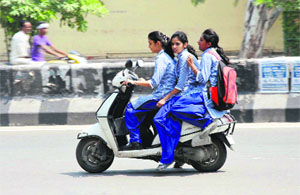 Three girl students ride a scooter in violation of traffic rules in Bathinda.