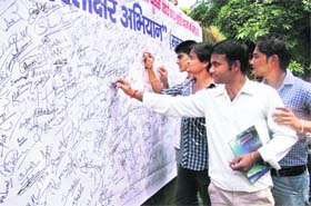 Students participate in a signature campaign against the lathi-charge on students in Dehradun on Saturday