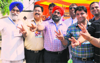 The newly elected president of the United Cycle and Parts Association, Charanjit Singh Vishivkarma (centre), flashes a victory sign in Ludhiana. Tribune photo: Himanshu Mahajan