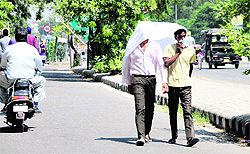 People walk in the sun after covering their head with a cloth to protect themselves from the heat in Bathinda; (right) women return home after a hard days work at village Nathana in the district