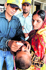 Volunteers of the Health Department administer polio drops to a child at the Ludhiana railway station