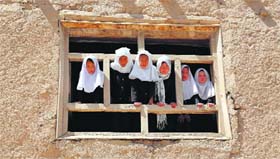 Afghan schoolgirls look on from the window of their school in Ghazni on Sunday.