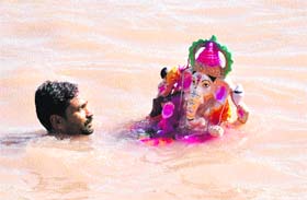 A devotee prepares to immerse an idol of Lord Ganesha in the Chenab in Akhnoor.