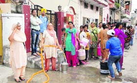 Residents of Kabir Nagar make a beeline outside a house where its owner used generator set for getting water supply in Jalandhar on Monday.