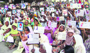 Women with photographs of debt-ridden farmers, who committed suicide, participate in a rally at New Grain Market in Sangrur on Monday.