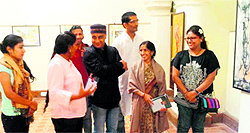 Visitors have a look at paintings during an exhibition at an art gallery in Shimla