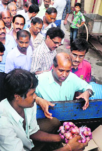 People buy onions sold by the Food Department at the subsidised rate of Rs 36 per kg in Kolkata on Wednesday. 