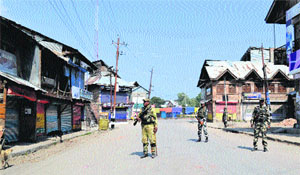 Security forces personnel patrol a street in curfew-bound Shopian town. 