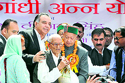 Chief Minister Virbhadra Singh hands over foodgrain to a beneficiary during the launch of the Rajiv Gandhi Ann Yojana in Shimla on Friday