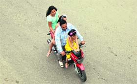 A couple with their two children ride a motorcycle without any of them wearing safety helmets at BC Road in Jammu on Friday.