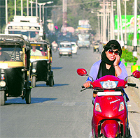 A girl uses a mobile phone while driving her scooter at Maulana Azad Road in Srinagar on Saturday