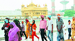 Devotees enjoy the rain at the Golden Temple in Amritsar on Sunday