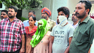 Accused Krishan Lal and Paramjit Kaur (faces covered) in police custody in Ludhiana on Sunday. 