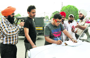 Assistant DTO Bhupinder Singh along with other officials issues challans to private vehicles ferrying passengers on shared basis in Bathinda on Tuesday morning. 