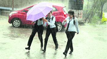 Students run for cover as it rains in Dharamsala on Tuesday. 