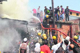 Fire fighters try to douse a fire at Nowhatta in Srinagar on Tuesday. Three houses and a shop were demaged in the fire caused by short circuit.