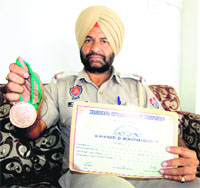 Surinderpal Singh shows a medal and certificate he won in Amritsar on Thursday. 
