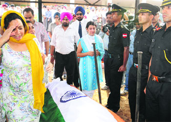 Lt Col Bikramjeet Singh's mother Luvpreet Kaur salutes his mortal remains as his wife Navneet (in blue dress) looks on during his cremation in Chandigarh on Friday