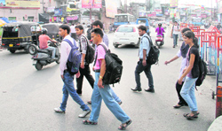 Pedestrians cross a busy Chakrata Road that has no zebra crossing in sight.