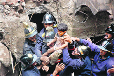 Firefighters rescue a boy after a BMC building collapsed in the Mazgaon area of Mumbai on Friday.