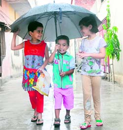 Children protect themselves from rain by holding an umbrella in Amritsar on Saturday.