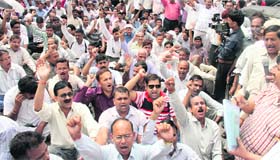 Uttarakhand government employees stage a protest outside the Secretariat in Dehradun on Friday.