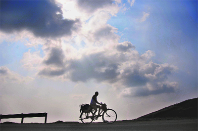 Forming a Silhouette: A man rides his bicycle amid dark clouds on the Jammu-Srinagar highway on Saturday. 