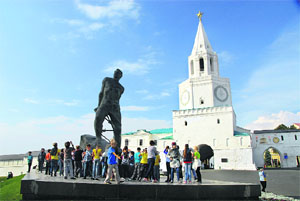 Children frolic around a statue of Tatar poet and freedom fighter Mulla Jalil in front of the Spasskaya Tower, entrance to the Kazan Kremlin