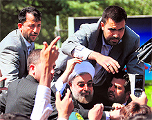 Bodyguards surround Iranian President Hassan Rouhani after a shoe was thrown towards his car in Tehran on Saturday