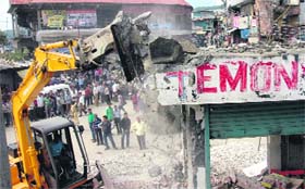 A JCB machine removes encroachment from the national highway in Pithoragarh city on Sunday