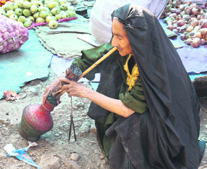 Smoke break: An elderly woman smokes hookah on a roadside in Srinagar on Monday.