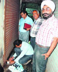 A House Tax team of the MC seals a shop near Lohgarh Gate area in Amritsar on Tuesday