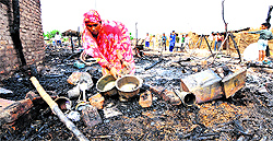A woman collects her belongings from her gutted hut