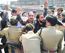 Police personnel try to detain protesting government employees outside the Assembly in Srinagar on Tuesday.
