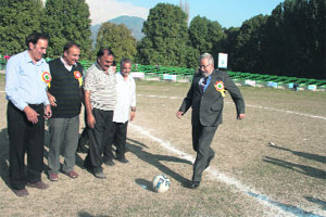 Sports Minister Taj Mohiuddin kicks a football before the start of a match in Srinagar on Tuesday.